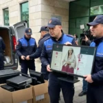 Σατιρική απεικόνιση: αστυνομικοί μεταφέρουν οθόνη με την υπουργό AI Diella